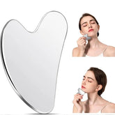 Woman using a heart-shaped gua sha on a white background
