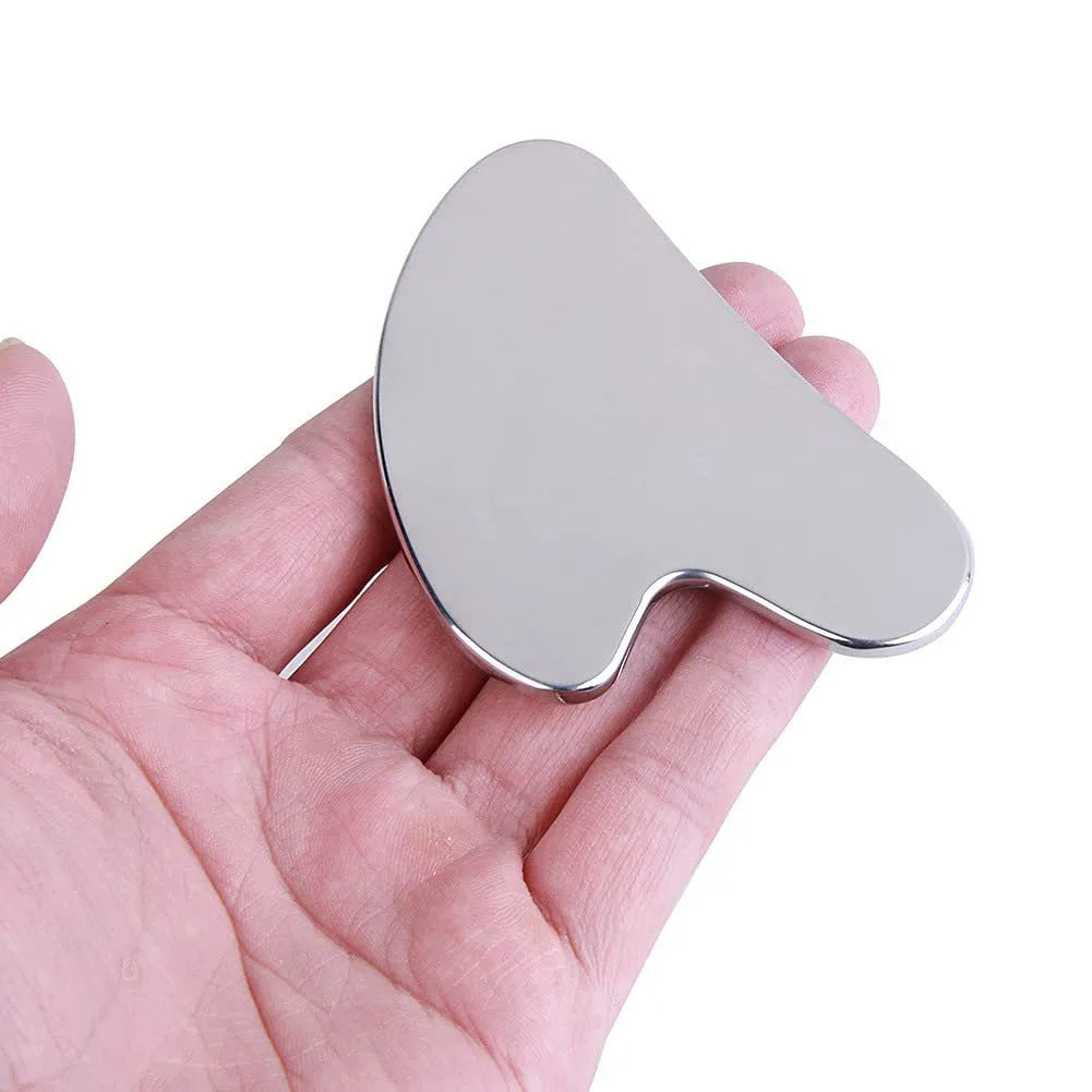Heart shaped stainless steel gua sha facial sculpting tool being held in a hand GlowNest Co